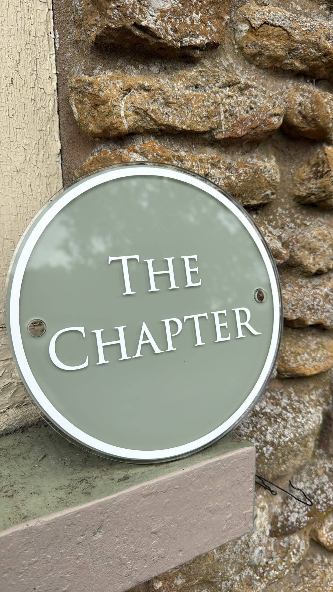 The sage-green hand-lettered sign that names the room The Chapter