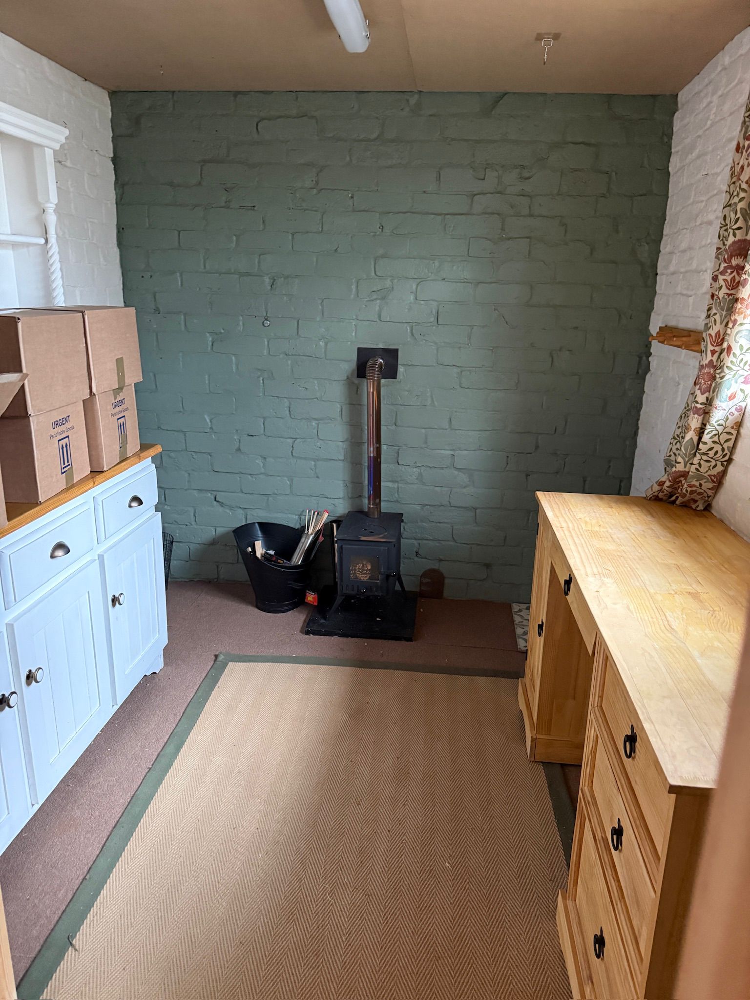 The little wood burner against a sage-painted brick wall